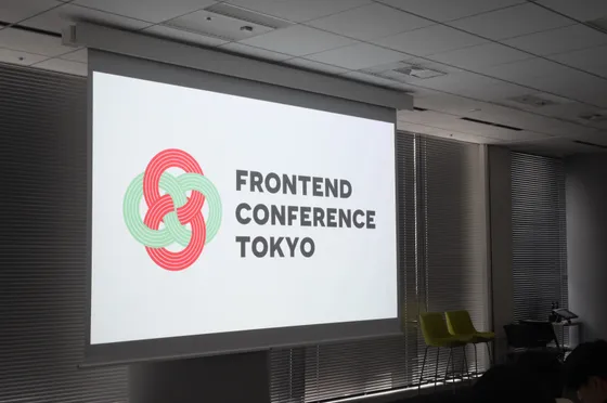 スクリーンに映ったカンファレンスのタイトルを見る参加者